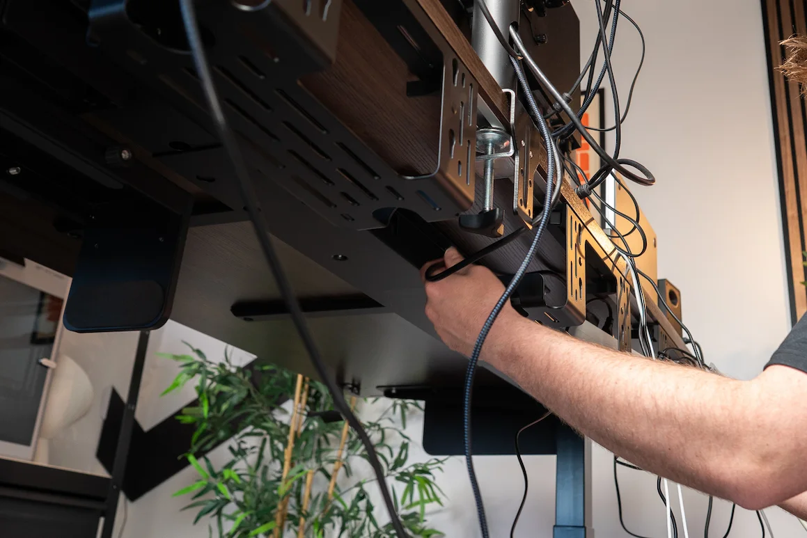 Hands organizing cables under the desk with multiple installed cable trays Hands organizing cables under the desk with multiple installed cable trays