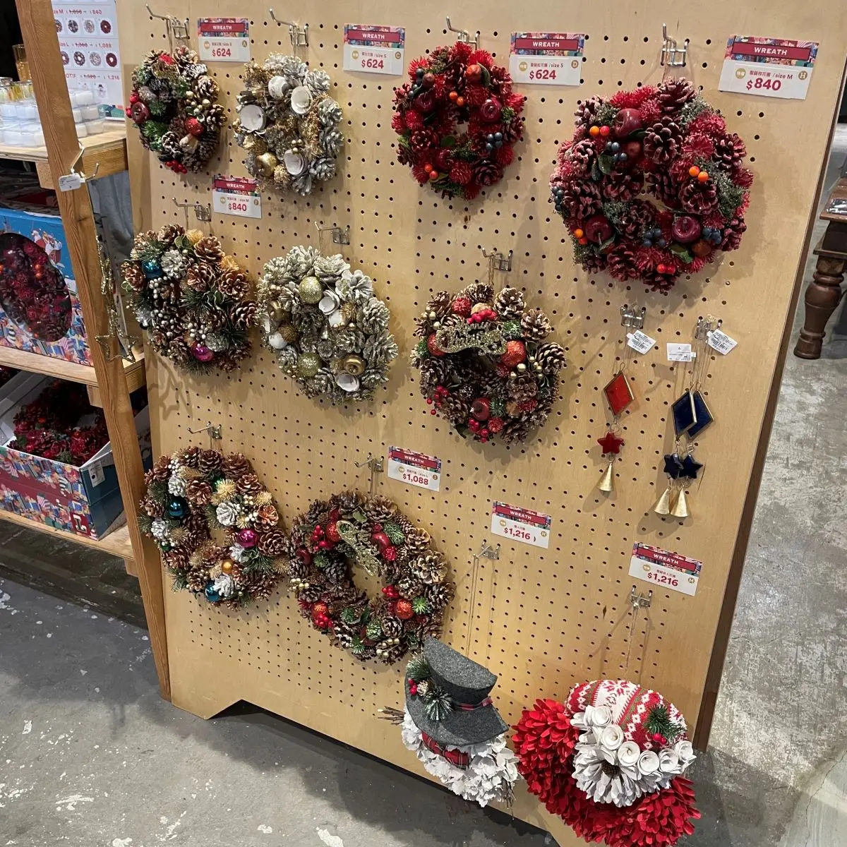 Espositore con pannello forato in legno utilizzato per appendere ghirlande decorative e ornamenti in un negozio.