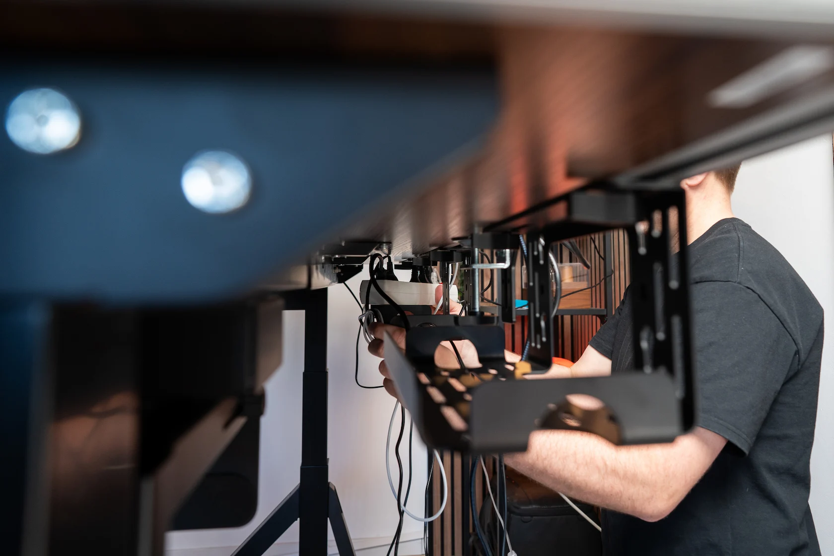 Under-desk view of multiple cable trays being installed on a standing desk Under-desk view of multiple cable trays being installed on a standing desk