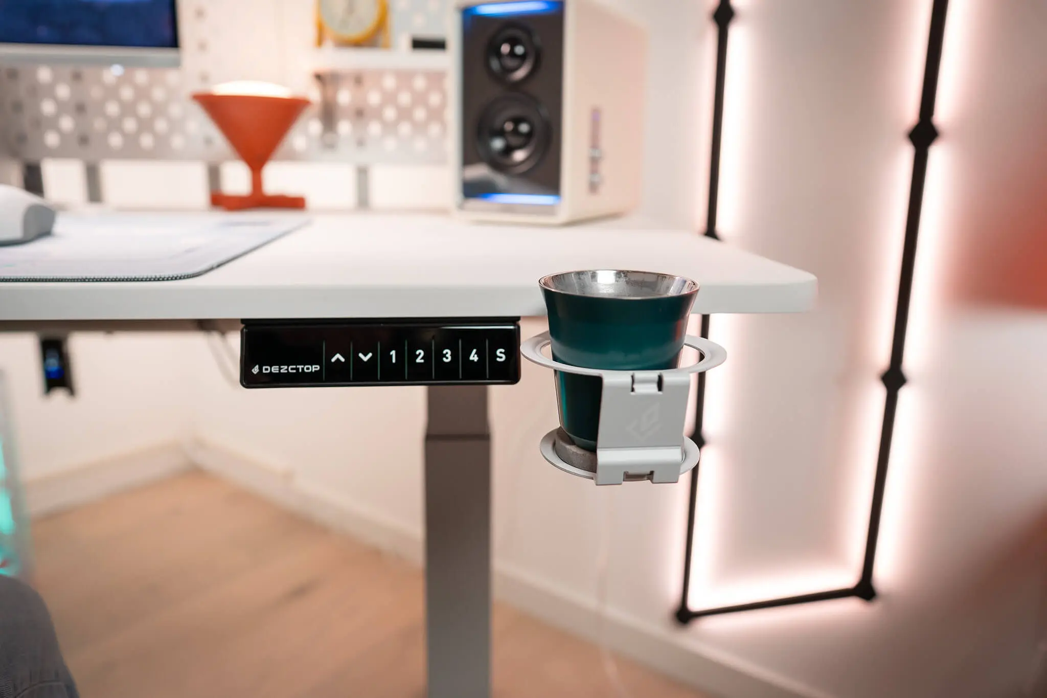 Dezctop Bifrost 升降桌的控制面板與磁吸式杯架特寫，展示便利的高度記憶功能與實用的桌邊配件設計。
