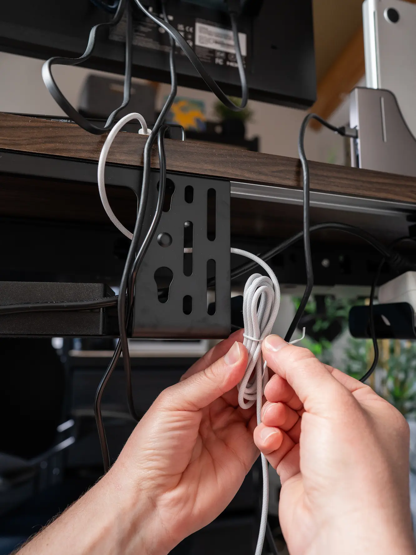 Hands holding a coiled cable beside a cable tray during cable organization Hands holding a coiled cable beside a cable tray during cable organization