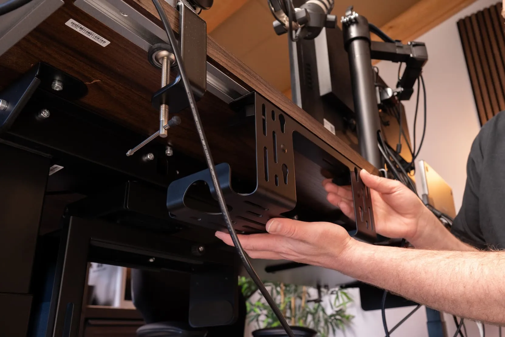Hands installing a DivMag Cable Management Tray under a Revon standing desk Hands installing a DivMag Cable Management Tray under a Revon standing desk