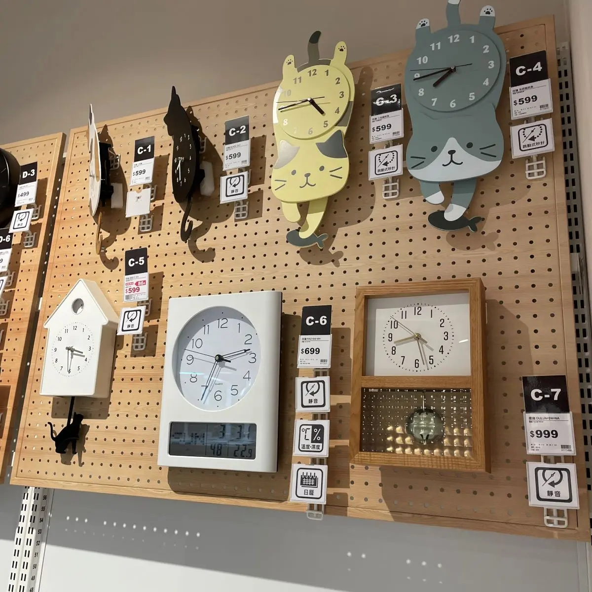 Pannello forato espositivo in legno con diversi orologi da parete in vendita, utilizzato per l’esposizione in negozio.