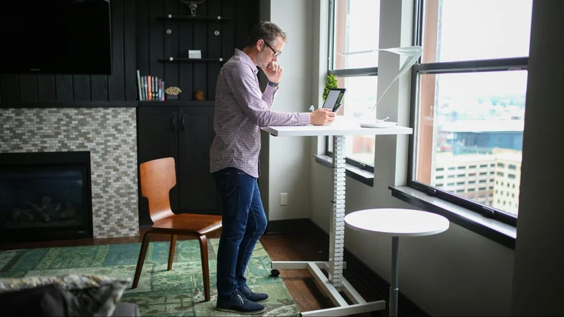 An image of a standing desk in a well-arranged home office, highlighting the benefits of reducing sedentary time and promoting workplace wellness.