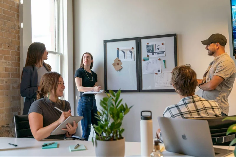 A group of people engaged in a discussion in an office setting, exchanging ideas and communicating with each other.
