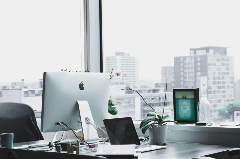 A home office setup featuring a desk with a computer, laptop, and plant for a productive work environment.