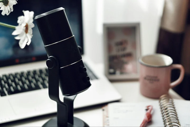 A microphone and laptop on a desk, perfect for a productive home office or remote work setup.