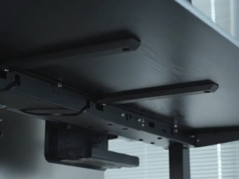 Under-desk view of Revon standing desk’s reinforced support bars and metal frame for enhanced stability.