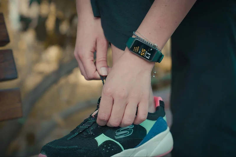 A person with a watch on their wrist tying their shoe, highlighting the importance of reducing sedentary time.