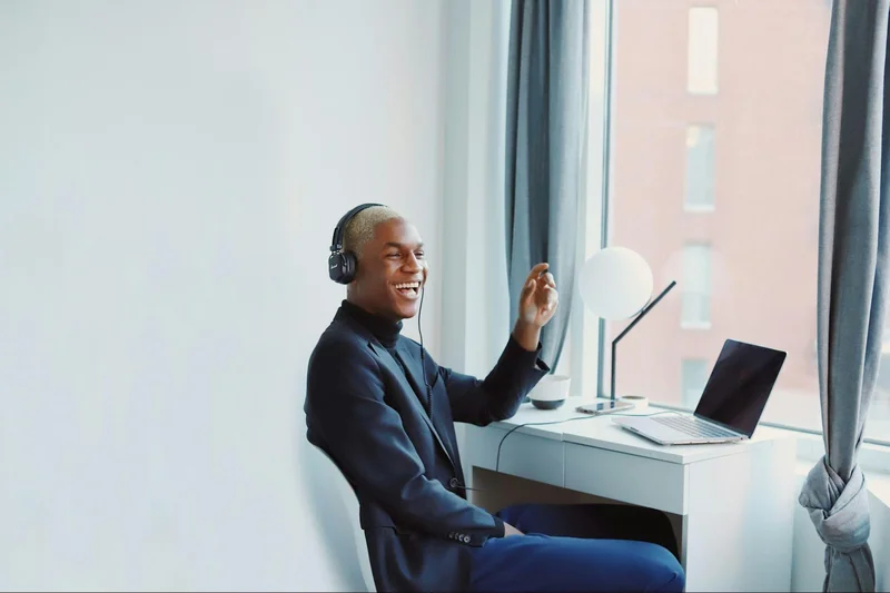 A man sitting at a desk with headphones on, part of a minimalist home office design.
