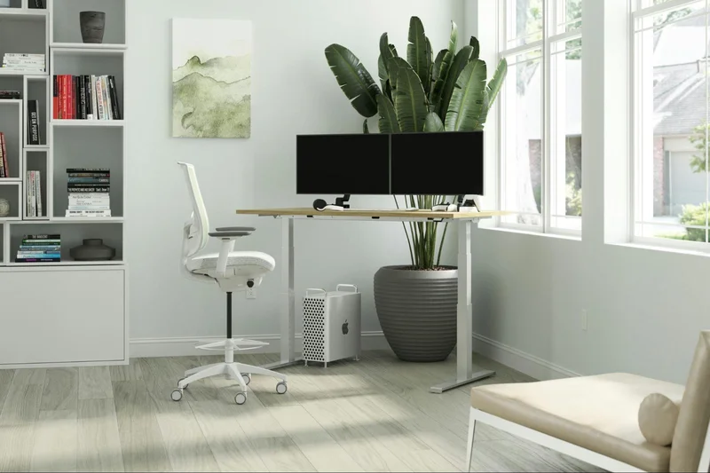 A white desk with a computer and a chair, emphasizing office ergonomics and healthy back habits.