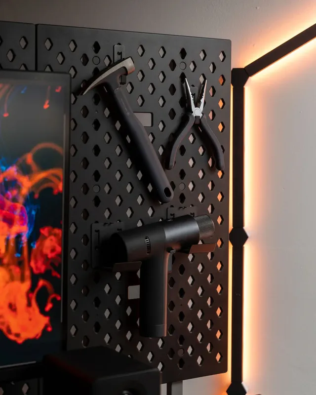 D-Board storage panel with hanging tools and accessories beside a monitor in a clean desk setup. D-Board storage panel with hanging tools and accessories beside a monitor in a clean desk setup.